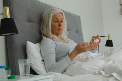 senior woman taking medicine in bedroom at home